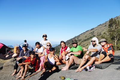 Group of people sitting against clear blue sky