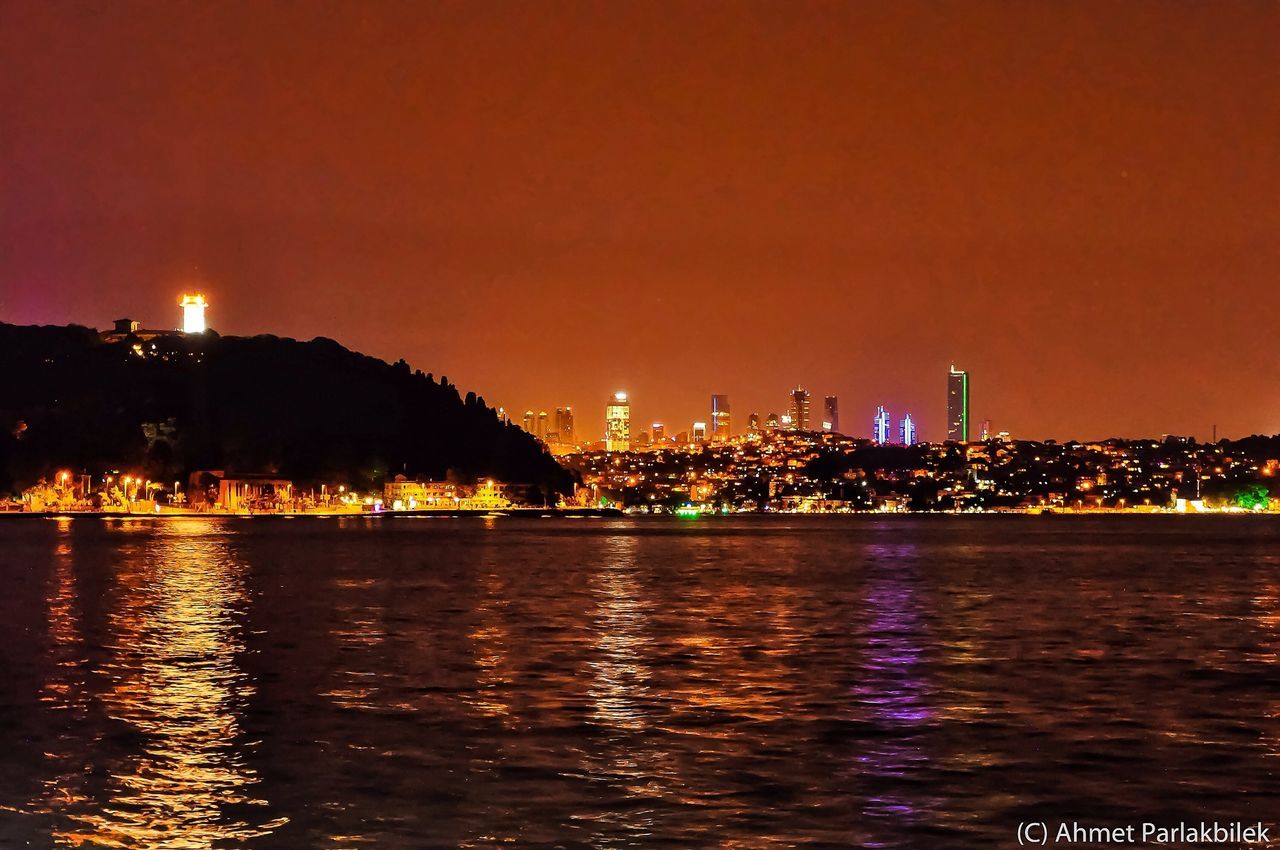 illuminated, building exterior, waterfront, architecture, city, water, night, built structure, cityscape, river, sea, reflection, urban skyline, skyscraper, copy space, sky, clear sky, tower, modern, residential building