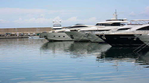 Boats moored at harbor against sky