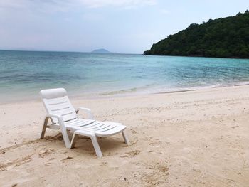 Chairs on beach against sky