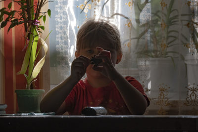 Girl holding pine cone while sitting at table