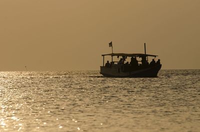 Boat sailing on sea against clear sky during sunset