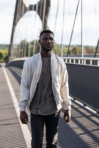 Portrait of young man standing on footbridge