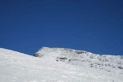 Low angle view of snow against clear blue sky