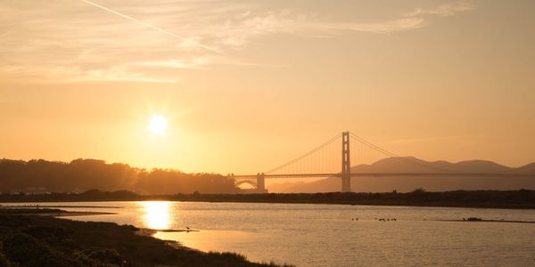 View of suspension bridge over river at sunset