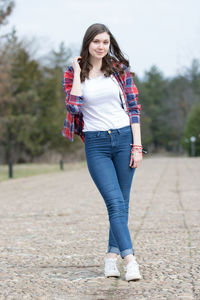 Full length of a smiling young woman against trees