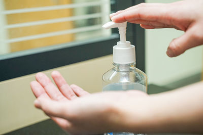 Close-up of person holding glass bottle against blurred background