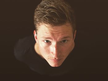 Close-up portrait of young man against black background