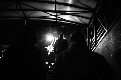 Rear view of people walking on steps towards illuminated stage