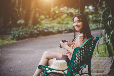 Young woman using phone while sitting on seat