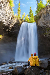 Rear view of man standing against waterfall