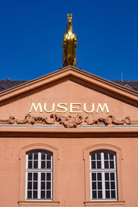 Low angle view of statue against building against clear blue sky