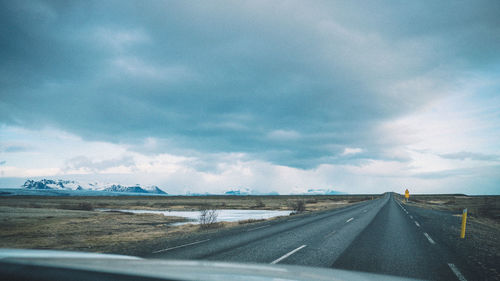 Road seen through car windshield against sky