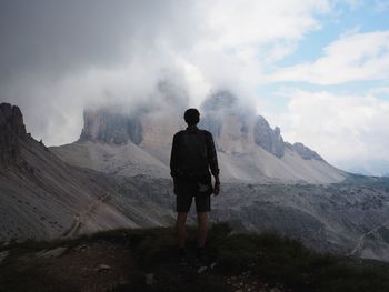 Rear view of man standing on mountain against sky