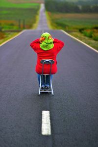 Rear view of girl sitting on chair over road