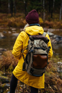 Traveler in a yellow raincoat with a backpack. camping in the woods. mountain hike. from behind