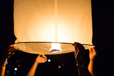 Friends holding paper lantern at night