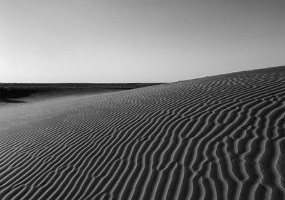 Scenic view of sand dunes against clear sky