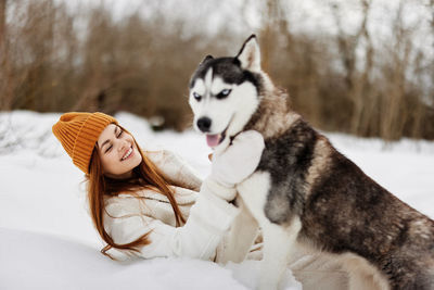 Portrait of woman with dog on snow