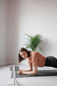 Portrait of young woman standing against wall