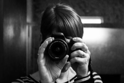 Close-up of woman photographing with dslr at home