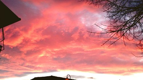 Low angle view of silhouette trees against cloudy sky