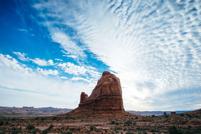 Rock formations on landscape against cloudy sky