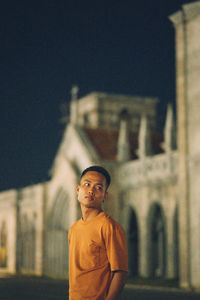 Portrait of man standing by building at night