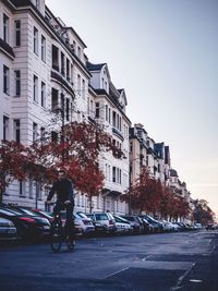 Cars on road by buildings against sky