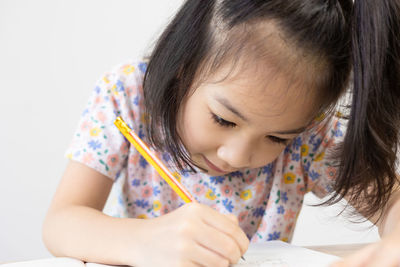 Close-up of girl drawing on book at home