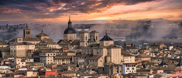 Aerial view of buildings in city of toledo, spain against sunlit cloudy sky