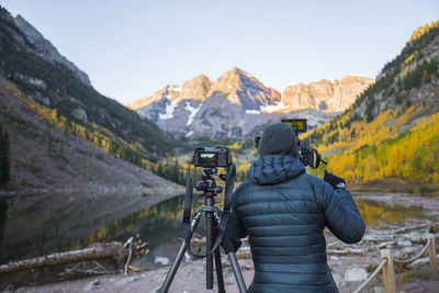 Rear view of man photographing with mountains in background