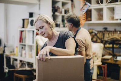 Female craftsperson with cardboard box in workshop