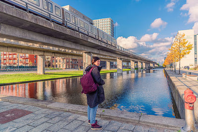 Woman stands near a canal near subway passes in the Ørestad city area in copenhagen, denmark