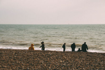 People standing on beach against clear sky