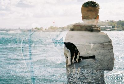 Double exposure of man and cat against sky