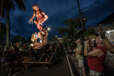 People on street against sky in city at night