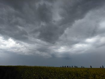 Scenic view of field against storm clouds