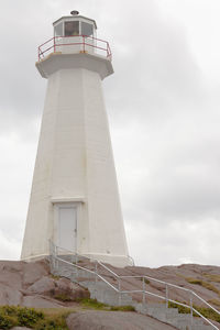Low angle view of lighthouse by building against sky
