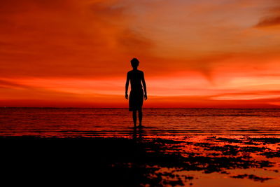 Silhouette man on beach against sky during sunset