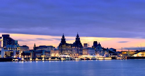 Illuminated buildings in city at sunset