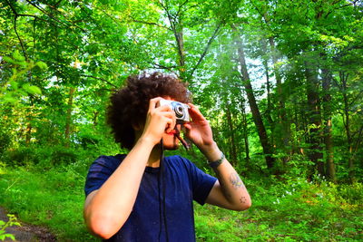 Man photographing while standing in forest