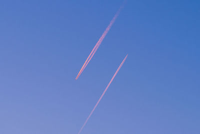 Low angle view of airplane flying against clear blue sky