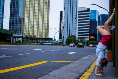 Rear view of woman walking on road against buildings in city