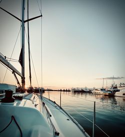 Sailboats moored in harbor at sunset