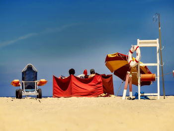 Rear view of people sitting on chair at beach