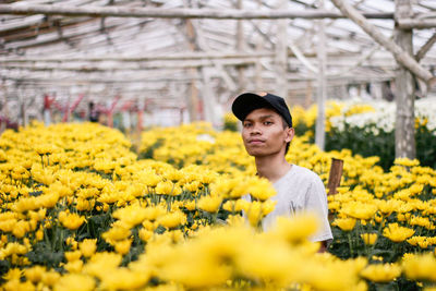 Portrait of man standing amidst yellow flowers