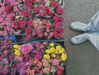 Low section of man standing by flower bouquets in crate at market stall