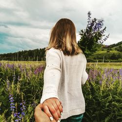 Midsection of woman standing on field against sky