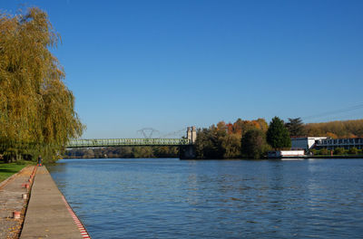 Bridge over river against clear blue sky